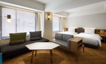 a modern hotel room with a large bed , couch , and table , all in neutral colors at Nohga Hotel Akihabara Tokyo