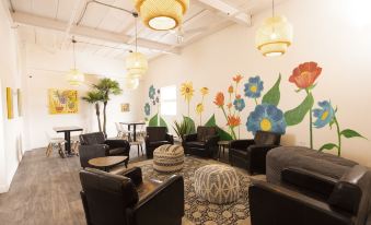 a cozy living room with black couches , a round coffee table , and a colorful mural on the wall at Hotel du Nord