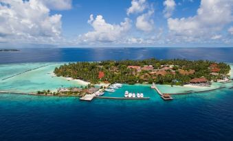 aerial view of a tropical island with a boat dock , surrounded by clear blue water and lush green vegetation at Kurumba Maldives