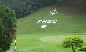 "a golf course with a large green field , trees , and a sign that says "" fhgc ""." at Shahzan Inn Fraser's Hill
