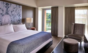 a large bed with a blue blanket is in a room with a window and a chair at The Fontaine