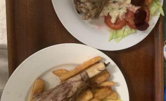two plates of food on a dining table , with one plate containing meat and fries and the other plate containing salad at Hillview Motel