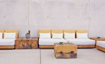 a white couch with yellow cushions is placed in front of a concrete wall , next to a small table at Amangiri