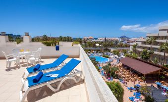 a balcony overlooking a pool and a beach , with several lounge chairs and umbrellas placed on the balcony at Hotel Best Tenerife