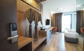 a modern hotel room with wooden flooring , minimalist furniture , and an open door leading to a bedroom at Fortune Hotel Buriram