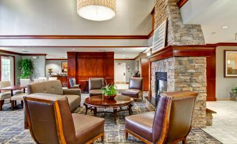 a cozy living room with brown leather chairs , a fireplace , and a large screen tv at Homewood Suites by Hilton Stratford