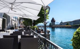 a restaurant with umbrellas is located near a body of water , providing shade and a pleasant atmosphere at Hotel des Balances