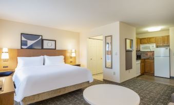 a hotel room with a large bed , white furniture , and a kitchenette in the background at Staybridge Suites Milwaukee Airport South