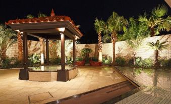 a well - maintained courtyard with a gazebo surrounded by lush greenery and palm trees at night at Grand Mercure Lake Hamana Resort & Spa