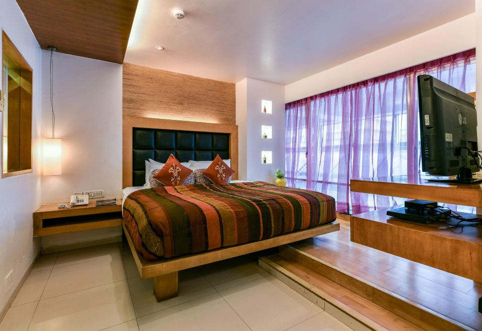 a large bed with a striped blanket is in a room with wooden walls and a window at The Regenza by Tunga