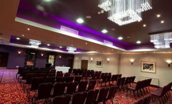 a large , well - lit conference room with rows of chairs arranged in a semicircle , ready for an event at Gloucester Robinswood Hotel, BW Signature Collection