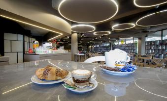 a cup of coffee , a croissant , and a teapot are on a dining table in a restaurant at The Gate Hotel