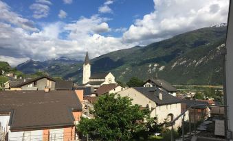 a picturesque town nestled in a valley with mountains and a church steeple visible in the background at Hotel du Soleil