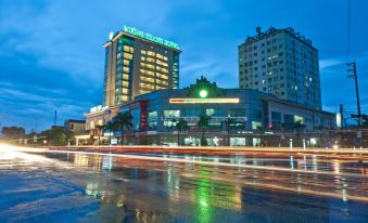 a city street with a large hotel building in the background , illuminated at night at Muong Thanh Dien Chau Hotel