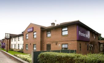 a brick building with a purple sign on the side and a fence in front of it at Premier Inn London Romford West