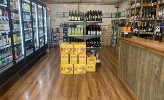 a grocery store with wooden floors , shelves filled with various products , and a large yellow bottle of wine on display at Warrego Hotel Motel Cunnamulla