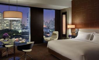 a spacious bedroom with expansive city views through large windows, featuring a comfortable bed positioned in the center at The Langham Shanghai Xintiandi