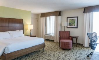 a hotel room with a bed , nightstands , and a chair , as well as a window and artwork on the walls at Hilton Garden Inn Plymouth