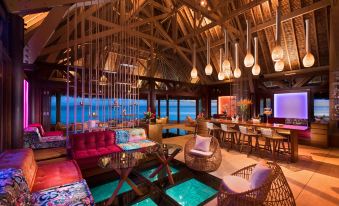 a modern , stylish living room with wooden ceiling and floor , large windows offering views of the ocean , and various furniture arrangements at Conrad Bora Bora Nui