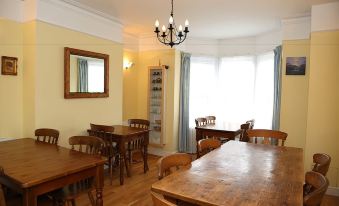 a dining room with wooden tables and chairs arranged around a large window , providing natural light and a comfortable atmosphere at Acorns Guest House