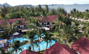 a tropical resort with multiple buildings , swimming pools , and palm trees , set against the backdrop of an ocean at Dolphin Bay Beach Resort