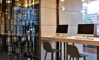 a modern office space with a desk and two chairs , along with a laptop on the desk at Hotel Amber Pattaya
