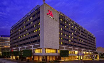 "a large , modern hotel building with a red sign that reads "" marriott "" prominently displayed on the front" at Athens Marriott Hotel
