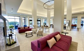 a large , well - lit living room with multiple couches and chairs arranged in various positions , creating a cozy atmosphere at Hilton Garden Inn Oconomowoc