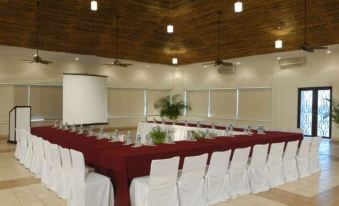 a conference room with a long table covered in a red tablecloth and white chairs at El Cid Marina Beach Hotel