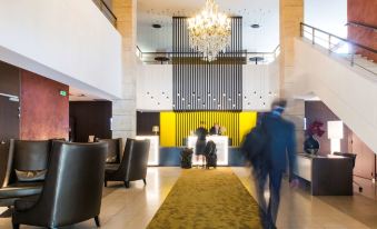 a modern hotel lobby with people sitting at tables , a reception desk , and a yellow bar area at Best Western Premier Hotel de la Paix