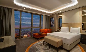 a modern bedroom with large windows offering a view of the city , a bed , and an orange sofa at Hilton Mall of Istanbul