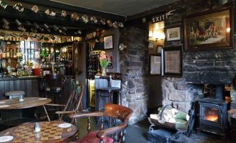 a cozy bar with stone walls , a fireplace , and various bottles of liquor on display at The Lamb Inn