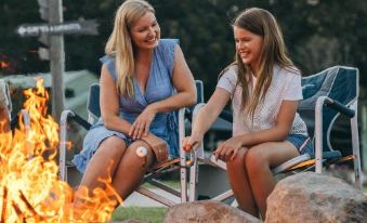 a woman and a young girl are sitting next to each other on a beach , enjoying each other 's company by the fire at Paradise Country Farmstay