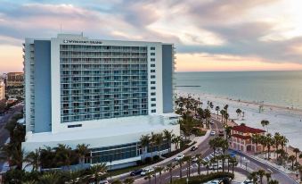 a large hotel with a white exterior and many windows is situated on the beach , overlooking the ocean at Wyndham Grand Clearwater Beach
