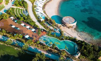 aerial view of a resort with multiple pools , lounge chairs , and umbrellas overlooking the ocean at Le Méridien Bodrum Beach Resort