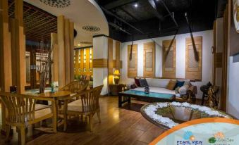 a cozy living room with wooden furniture , including a couch , chairs , and a dining table at Pearl View Hotel Prai, Penang