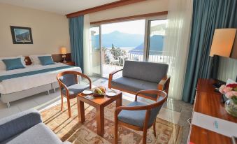 a cozy living room with blue couches , a dining table , and a balcony overlooking a beautiful view at Happy Hotel Kalkan