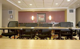 a conference room with multiple rows of chairs arranged in front of a long wooden table at Hotel Executive Suites