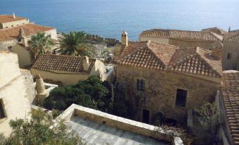 a picturesque coastal village with stone houses and palm trees , set against the backdrop of a clear blue sea at Casa Palma