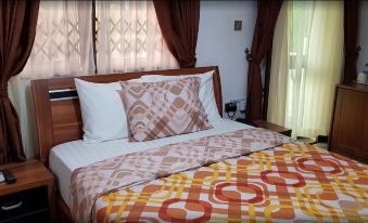 a bed with a white and brown quilt and pillows is shown in front of curtains at Ibisa Hotel