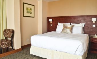 a large bed with white sheets and a wooden headboard is in a hotel room at Leisure Inn