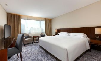 The bedroom is furnished with a bed, desk, and large windows at Sheraton Grand Taipei Hotel