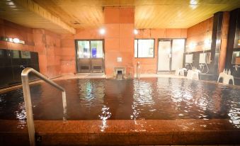 a large indoor hot tub filled with water and surrounded by wooden walls , creating a relaxing atmosphere at Fukui Hotel
