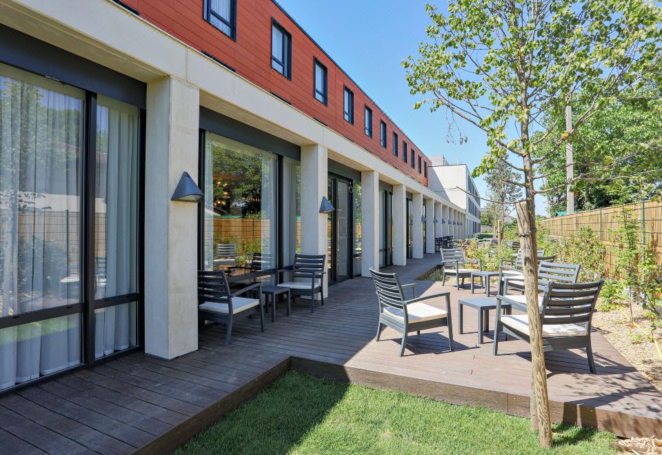 a courtyard surrounded by buildings , with several tables and chairs set up for outdoor dining at Hampton by Hilton Toulouse Airport