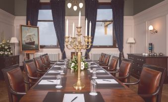 a conference room with a long wooden table , chairs , and a candelabra , set for a meeting at Titanic Hotel Belfast