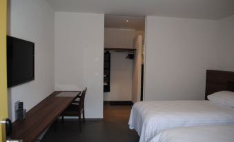 a hotel room with two beds , a desk , and a closet , all in a minimalist style at Hotel du Soleil