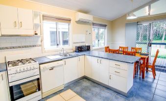 a kitchen with white cabinets , a sink , stove , oven , and window is shown with blue countertops at Reflections Jimmys Beach - Holiday Park