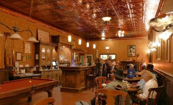 a large , dimly lit room with wooden walls and a bar counter where people are sitting and enjoying themselves at Tombstone Monument Guest Ranch