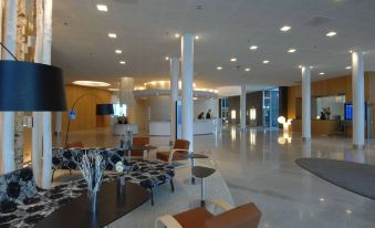 a large , modern lobby with high ceilings , white columns , and modern furniture arranged around tables at Hilton Helsinki Airport