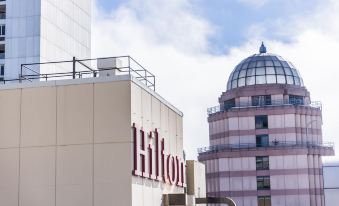 "a large building with the word "" hilton "" prominently displayed on its side , surrounded by other buildings and a blue sky" at Hilton San Francisco Union Square